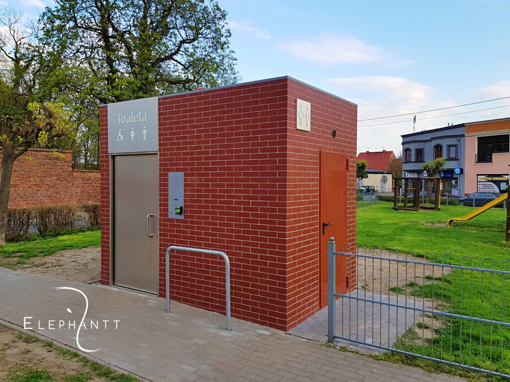 Automatyczna jednostanowiskowa prostokątna toaleta miejska City S1 we Wschowie przy Placu Grunwaldu. Elewacja wykonana z płytek gresowych.